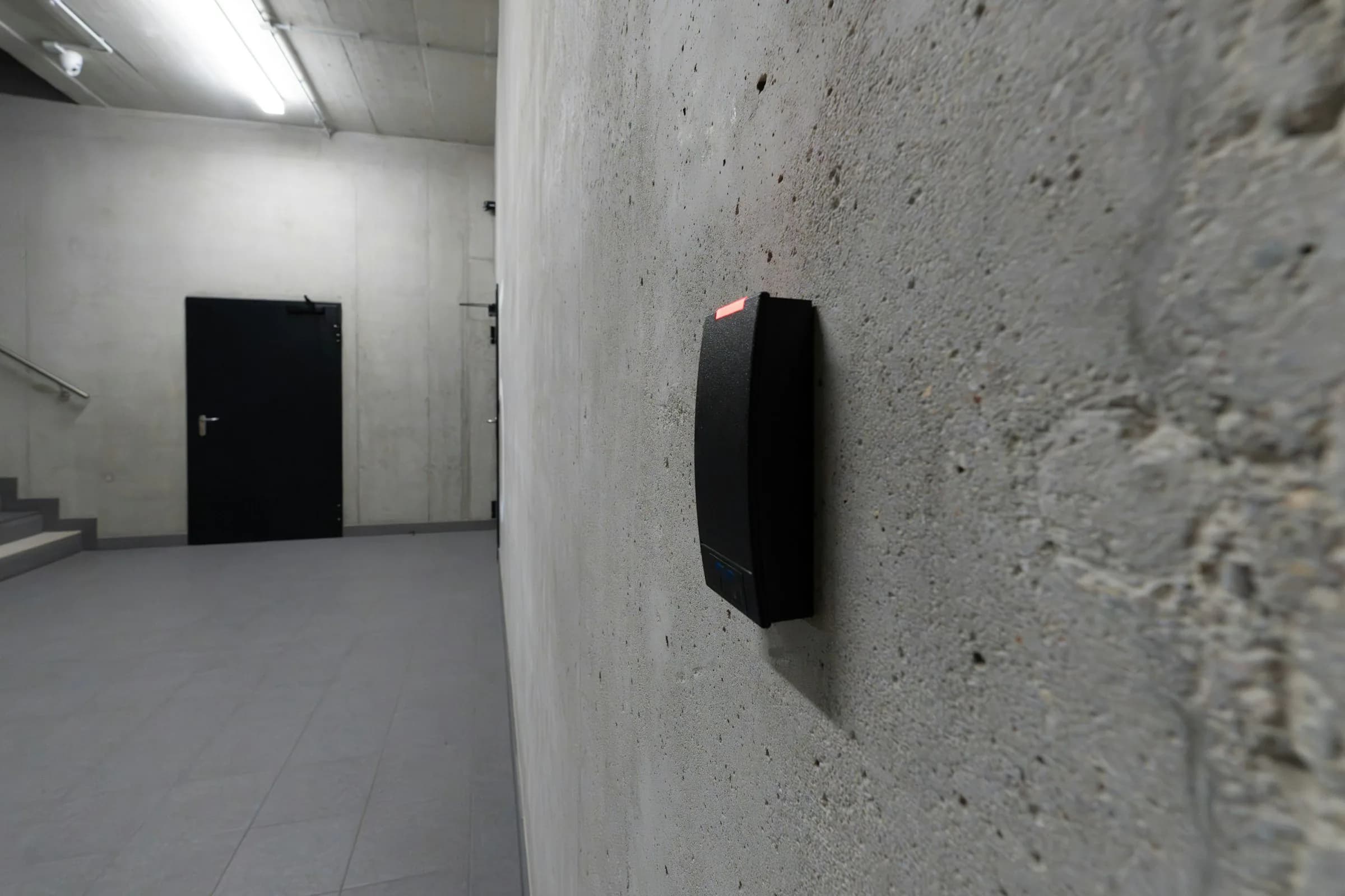 Modern access-control reader installed beside a secure concrete stairwell door