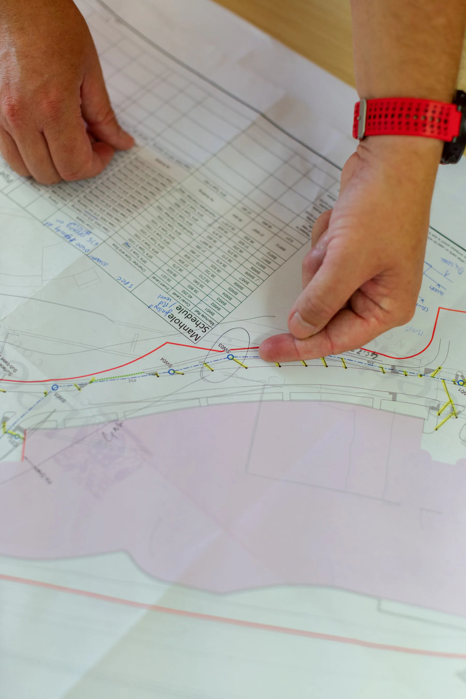 Engineer reviewing a marked technical site plan and equipment schedule